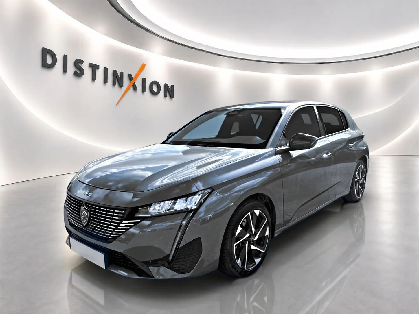 Peugeot 308 gris 3/4 avant droit, avec calandre distinctive et jantes alliage modernes.