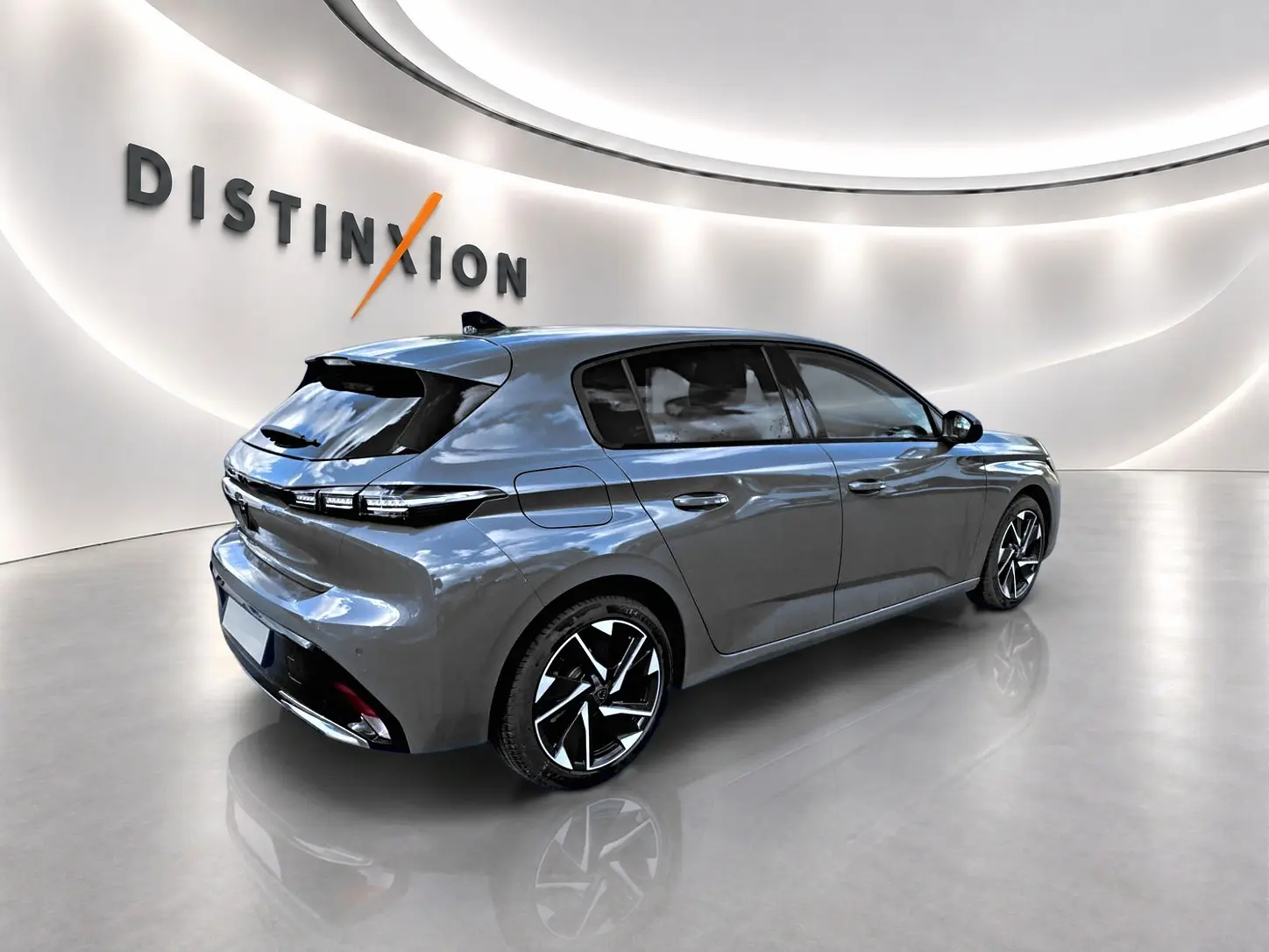 Peugeot 308 gris vue 3/4 arrière droit dans un showroom lumineux avec jantes alliage noires et détails LED.