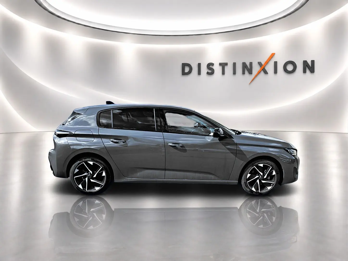 Profil droit d'une Peugeot 308 gris métallisé 2025 dans un studio lumineux avec jantes alliage noires et logo Distinxion en arrière-plan.