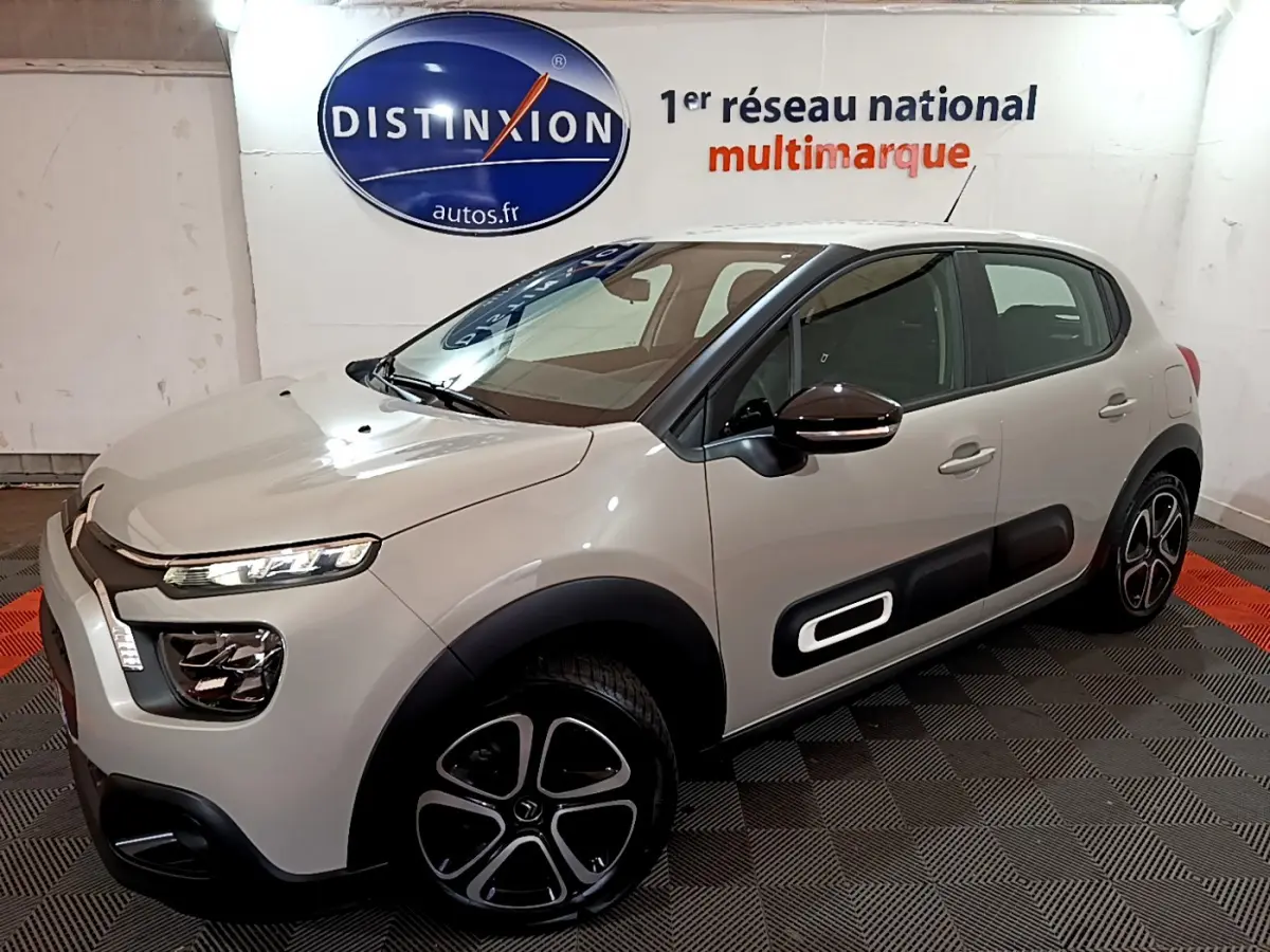 Citroën C3 beige vue 3/4 avant droit, avec protections latérales noires et jantes distinctives en alliage.