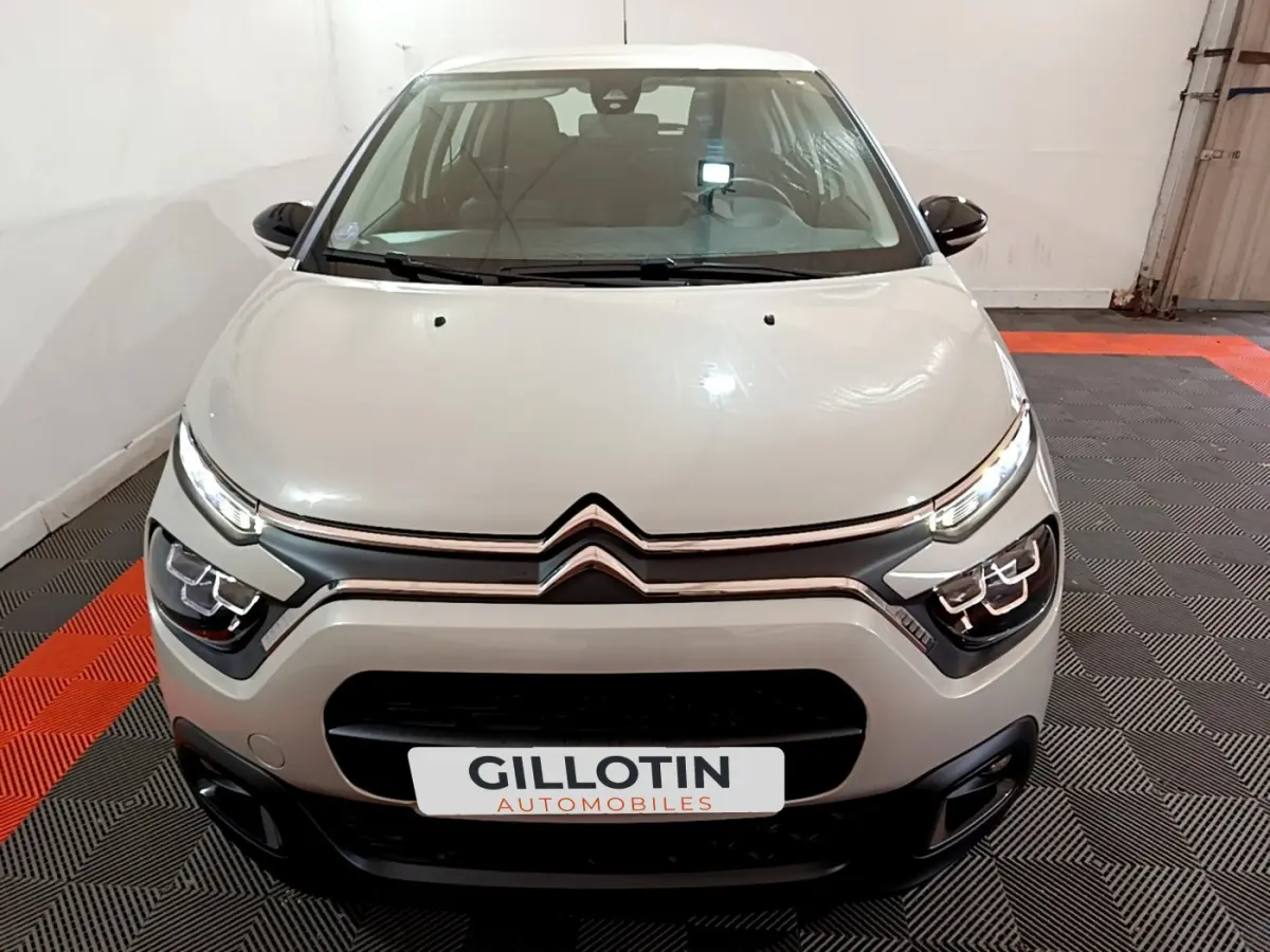 Vue avant d'une Citroën C3 beige 2022 avec feux LED et calandre noire dans un showroom intérieur.