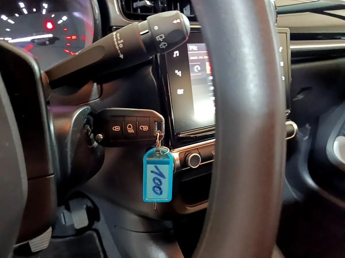 Vue rapprochée du volant et du tableau de bord noir de la Citroën C3 avec clé insérée et écran tactile allumé.