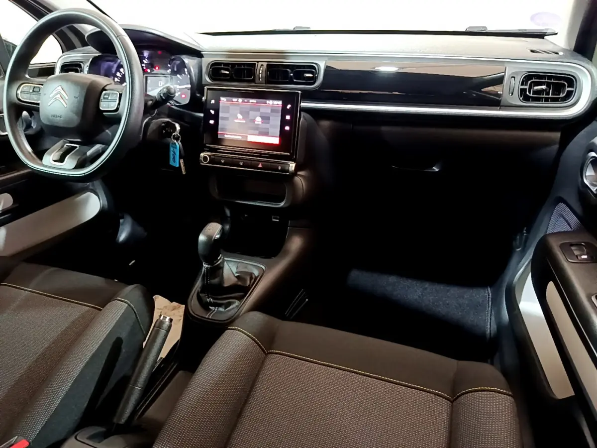 Vue intérieure avant droite du tableau de bord et volant noir de la Citroën C3 avec écran tactile central et sièges tissu.