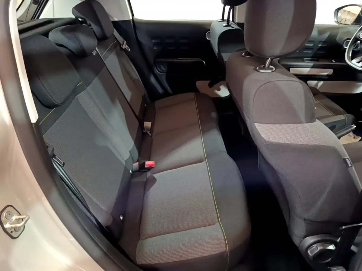 Vue intérieure arrière gauche sur les sièges noirs avec surpiqûres jaunes d'une Citroën C3 beige 2022 Feel Pack.