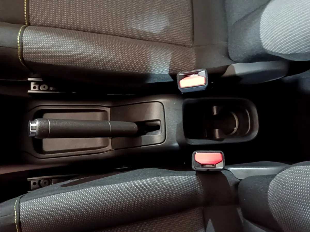 Vue plongeante sur la console centrale noire avec frein à main et ceintures rouges de la Citroën C3 beige 2022