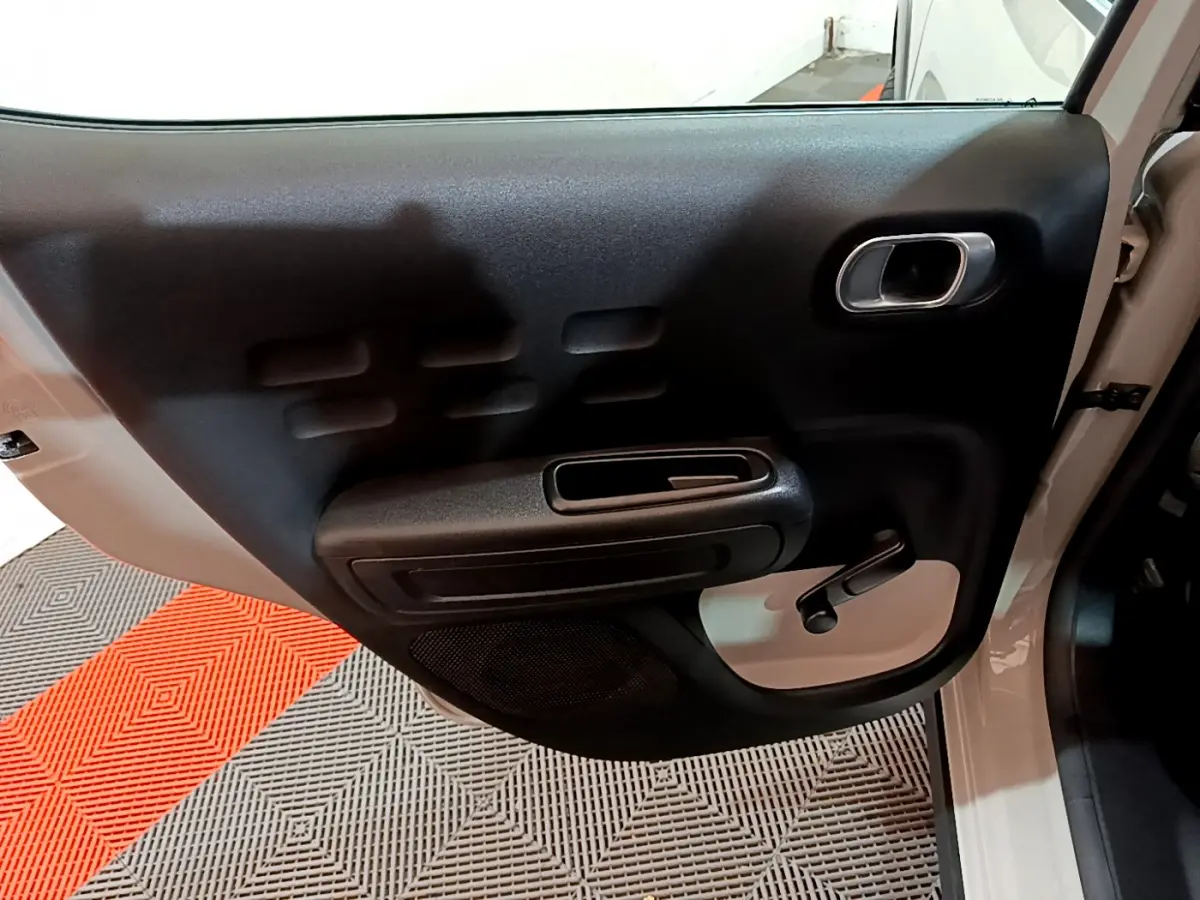 Vue rapprochée de la porte arrière gauche beige de la Citroën C3 2022 avec poignée manuelle et accoudoir noir.