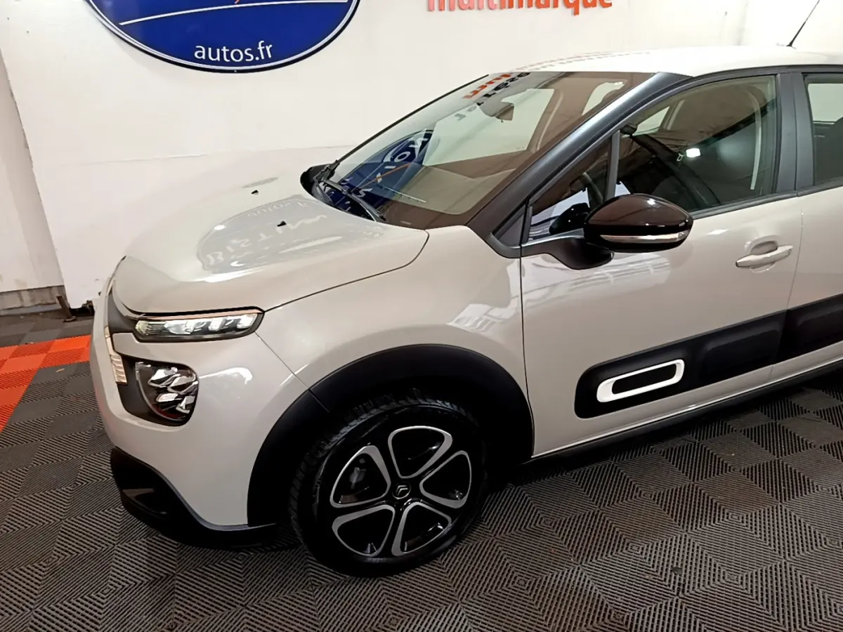 Vue 3/4 avant droit d'une Citroën C3 beige 2022 avec protections latérales noires et jantes alliage distinctives.