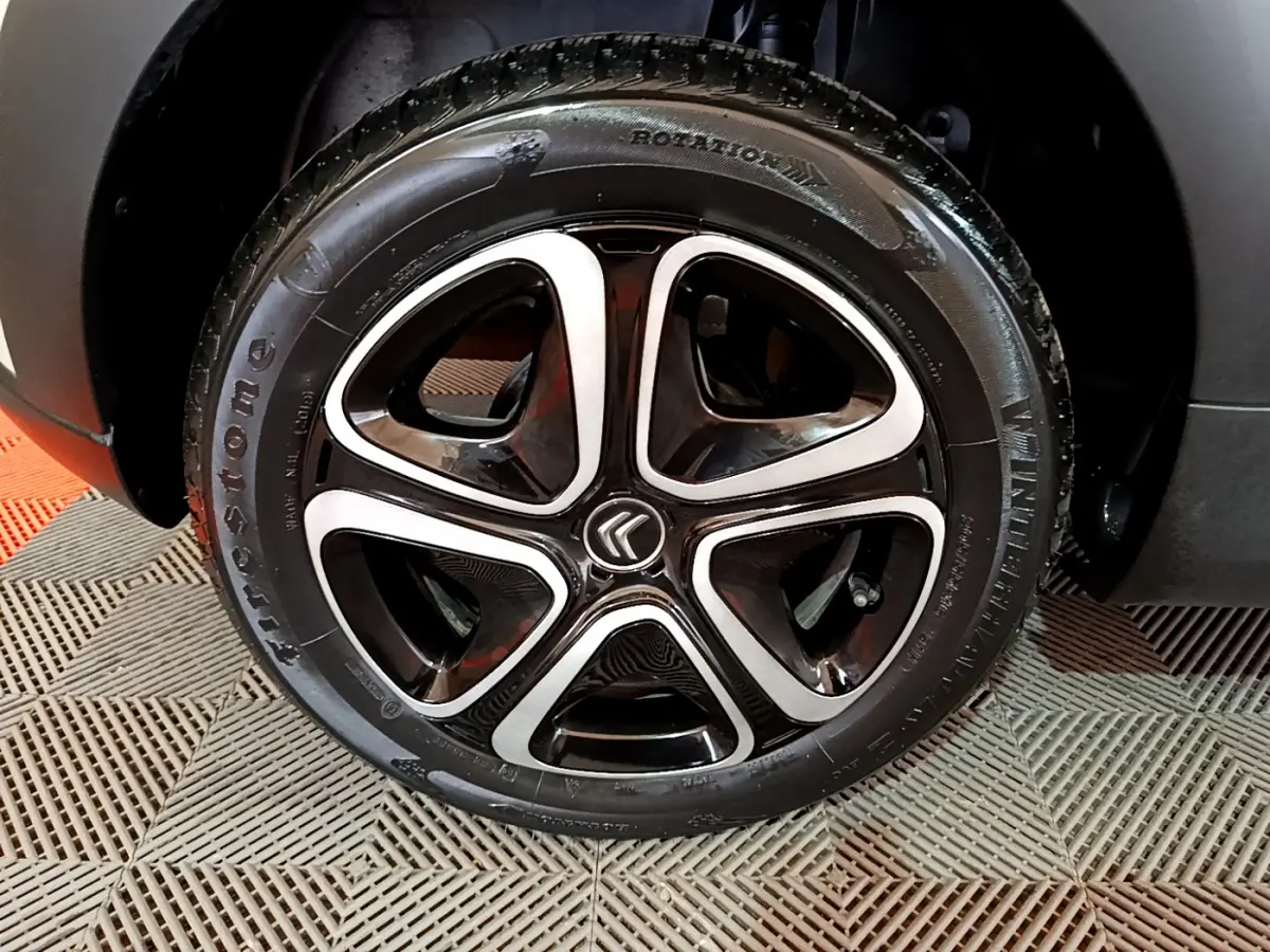 Gros plan sur la roue avant droite d'une Citroën C3 beige 2022 avec jante alliage noire et argentée distinctive.