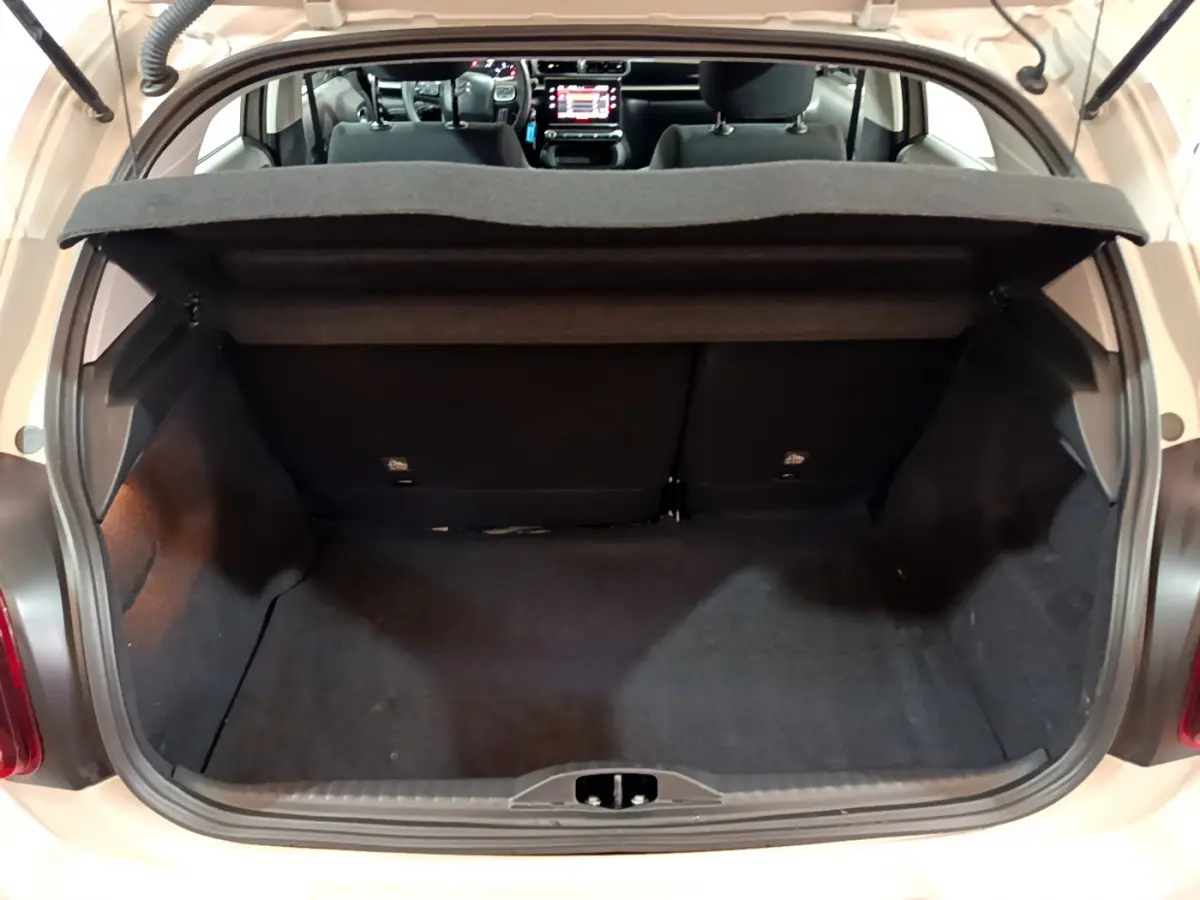 Coffre ouvert d'une Citroën C3 beige 2022, vue arrière montrant l'habitacle et l'écran tactile du tableau de bord.