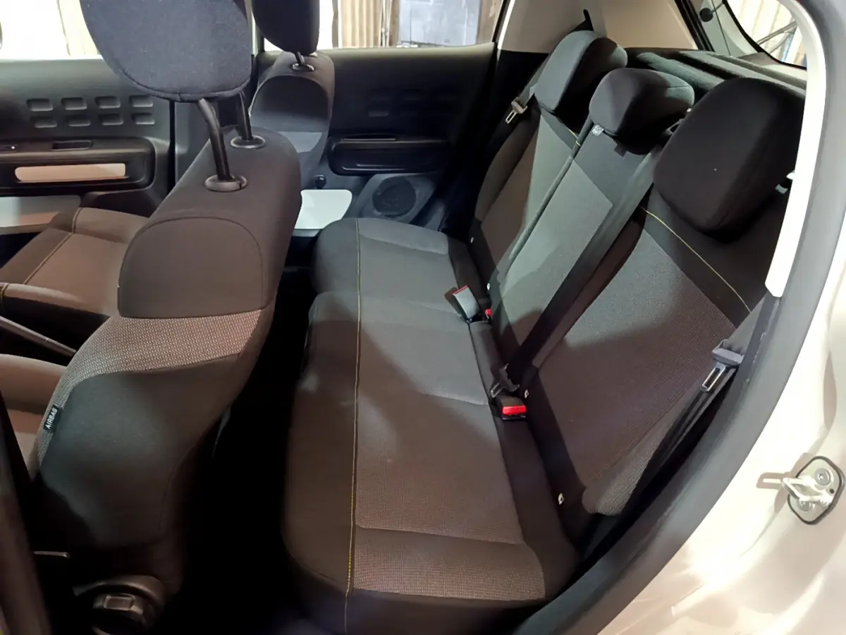 Vue intérieure côté droit sur la banquette arrière grise de la Citroën C3 beige, avec appuie-têtes et ceintures visibles.