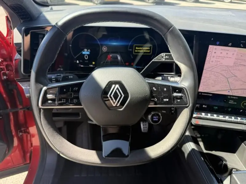 Vue centrée sur le volant du Renault Austral rouge flamme 2023, avec tableau de bord numérique et écran tactile visible.