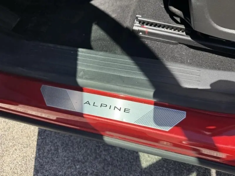 Gros plan sur la plaque de seuil de porte "ALPINE" du Renault Austral rouge flamme, côté intérieur avant droit.