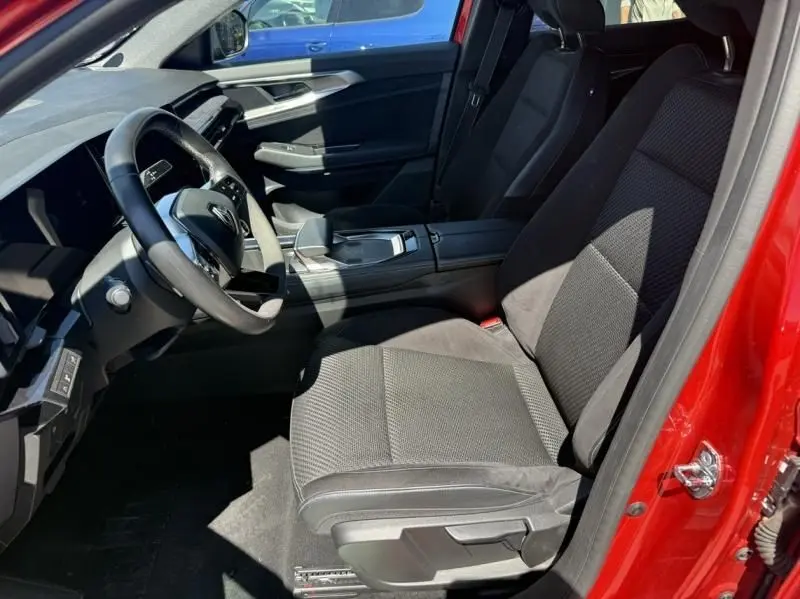 Vue intérieure côté conducteur du Renault Austral 2023 rouge flamme, montrant siège, volant et console centrale moderne.