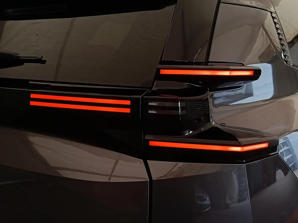 Gros plan sur le feu arrière droit rouge lumineux d'une Citroën C5 hybride gris foncé 2025.