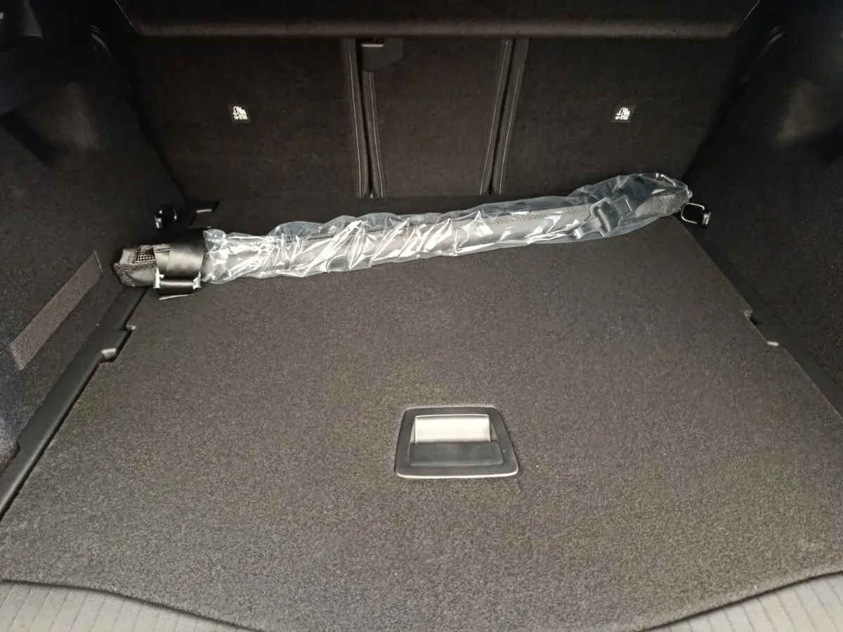Vue intérieure du coffre gris foncé de la Citroën C5 Hybride 2025 avec un parapluie emballé posé à plat.