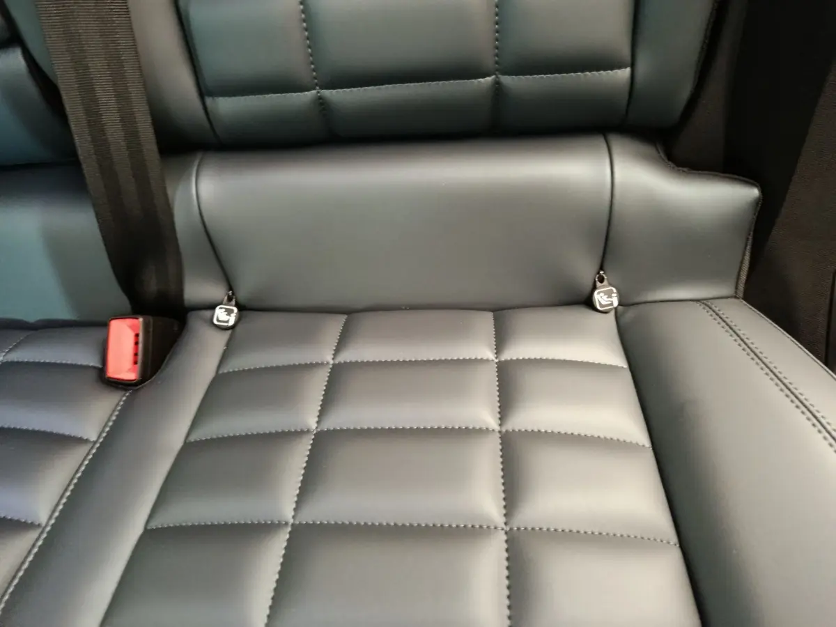 Gros plan sur la banquette arrière en cuir gris foncé de la Citroën C5 Hybride 2025 avec ceintures et ancrages Isofix visibles.