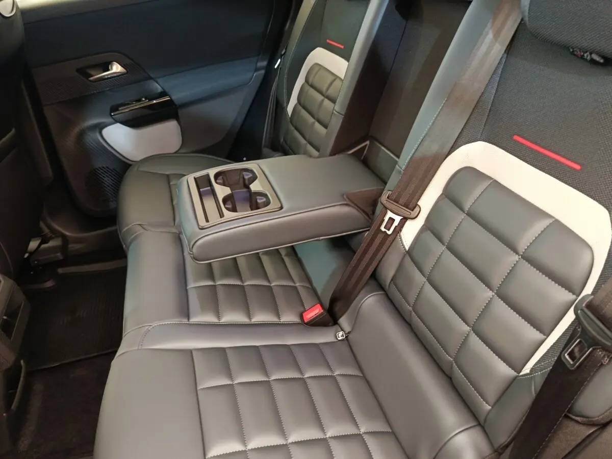 Vue intérieure sur la banquette arrière gris foncé de la Citroën C5 Hybride avec accoudoir central et porte-gobelets intégrés.