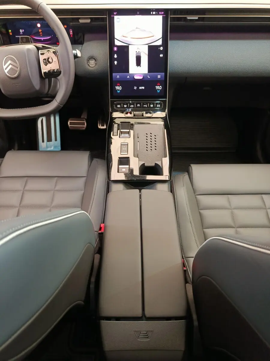 Vue intérieure centrée sur la console centrale et le volant cuir du Citroën C5 hybride gris foncé, avec écran tactile vertical.