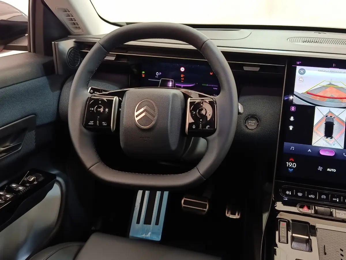 Vue intérieure centrée sur le volant cuir multifonctions et l'écran tactile du tableau de bord de la Citroën C5 Hybride 2025.