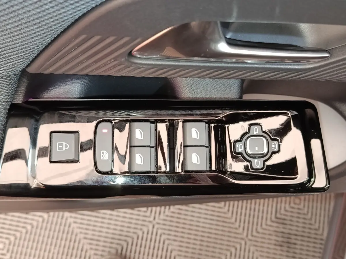 Gros plan sur les commandes de lève-vitres et rétroviseurs côté conducteur d'une Citroën C5 hybride gris foncé.
