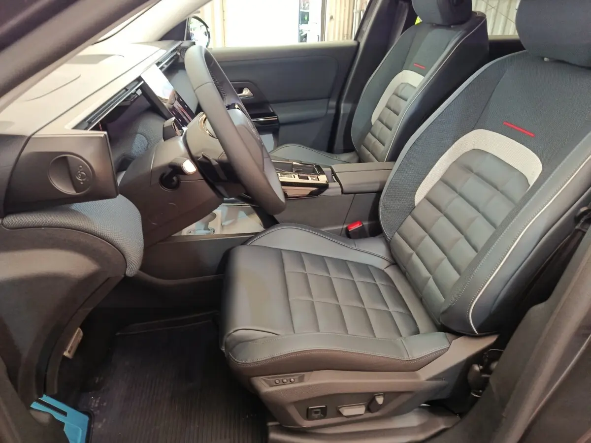 Vue intérieure côté conducteur du Citroën C5 Hybride 2025, sièges cuir gris avec surpiqûres rouges et tableau de bord moderne.