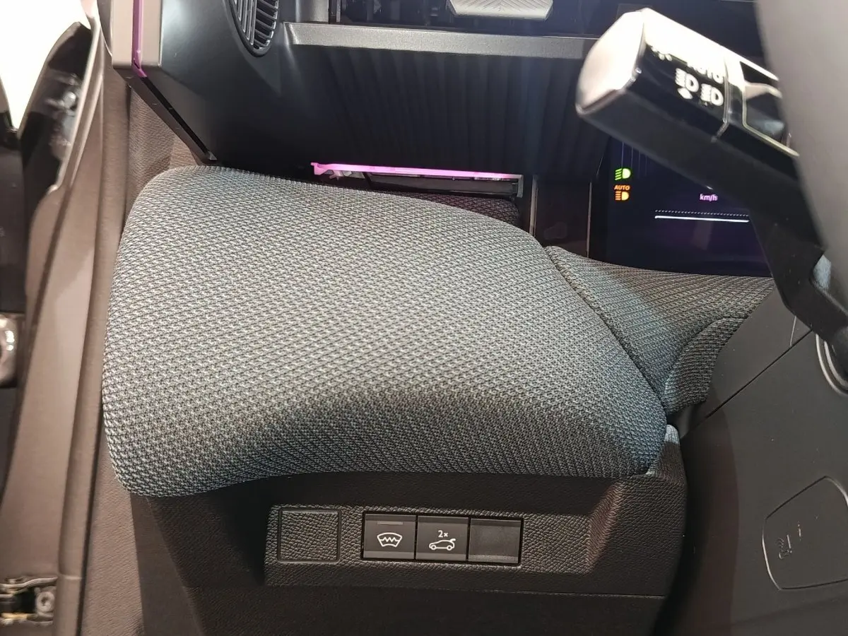 Gros plan sur la commande d'ouverture du coffre et dégivrage, siège conducteur gris foncé de la Citroën C5 hybride 2025.