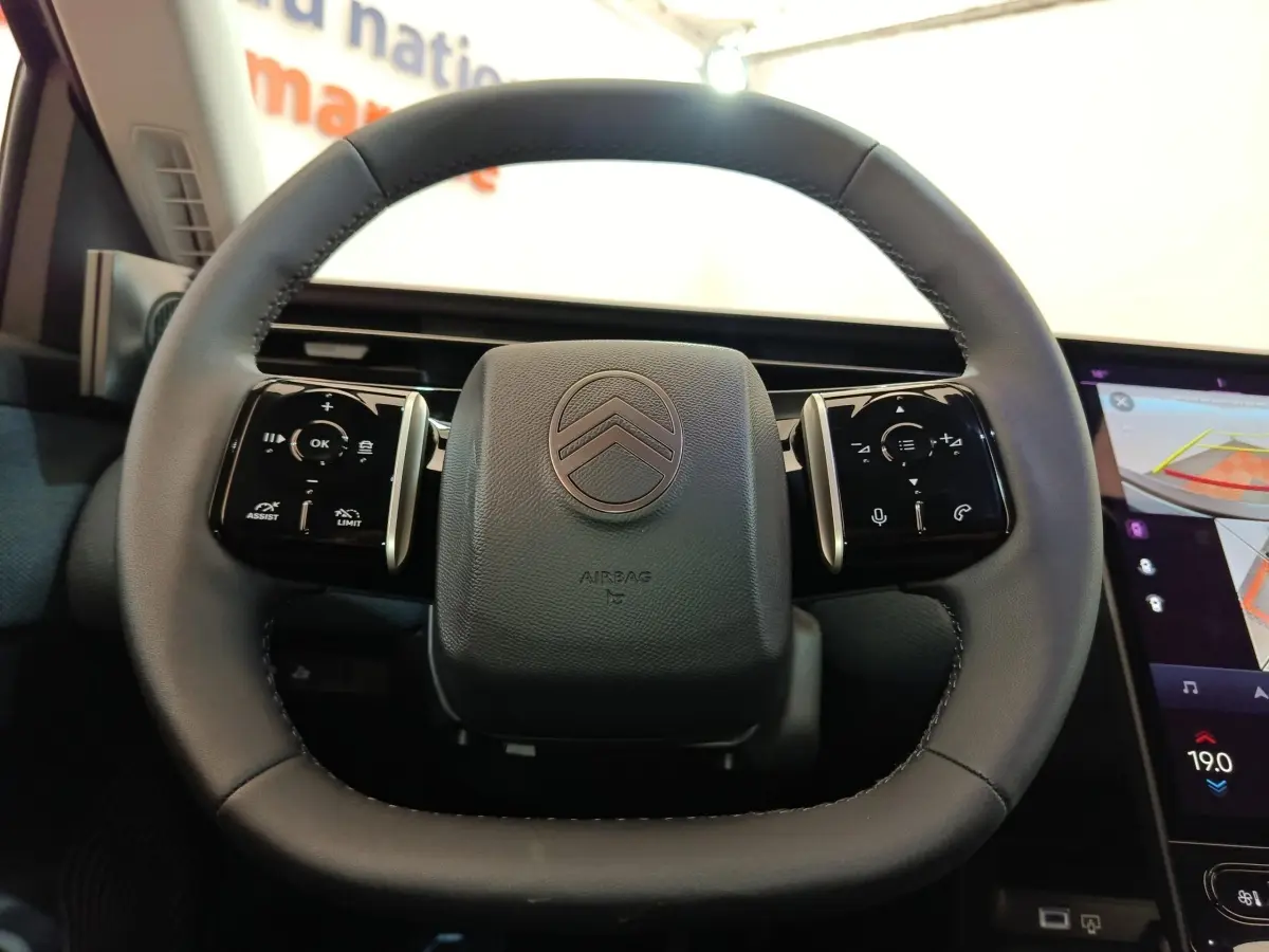 Volant cuir noir de Citroën C5 Hybride 2025 vu de face avec commandes tactiles et écran tactile latéral visible.