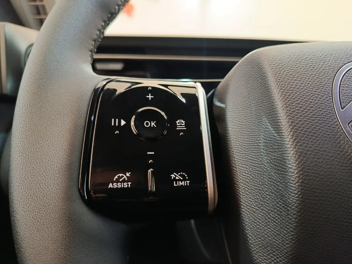 Gros plan sur les commandes multifonctions du volant cuir gris foncé de la Citroën C5 hybride 2025.