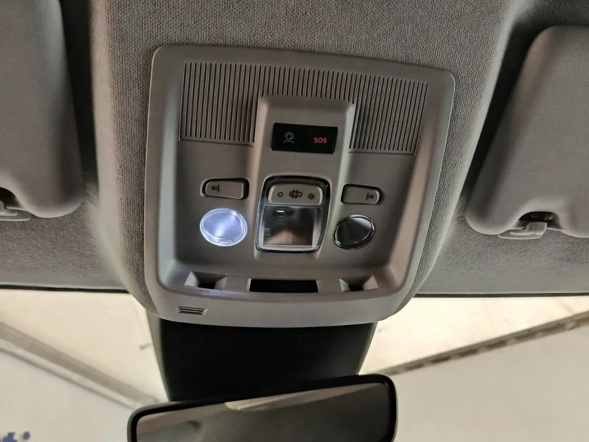 Vue intérieure en plongée sur la console de toit gris clair avec boutons d’éclairage et alerte SOS de la Citroën C5 hybride.