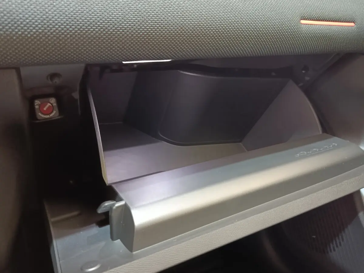 Vue rapprochée de la boîte à gants ouverte côté passager dans l’habitacle sombre d’une Citroën C5 Hybride gris foncé.