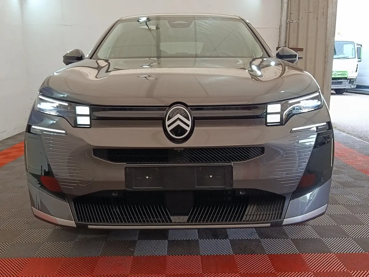 Vue frontale d'une Citroën C5 hybride gris foncé avec phares LED allumés et calandre distinctive.