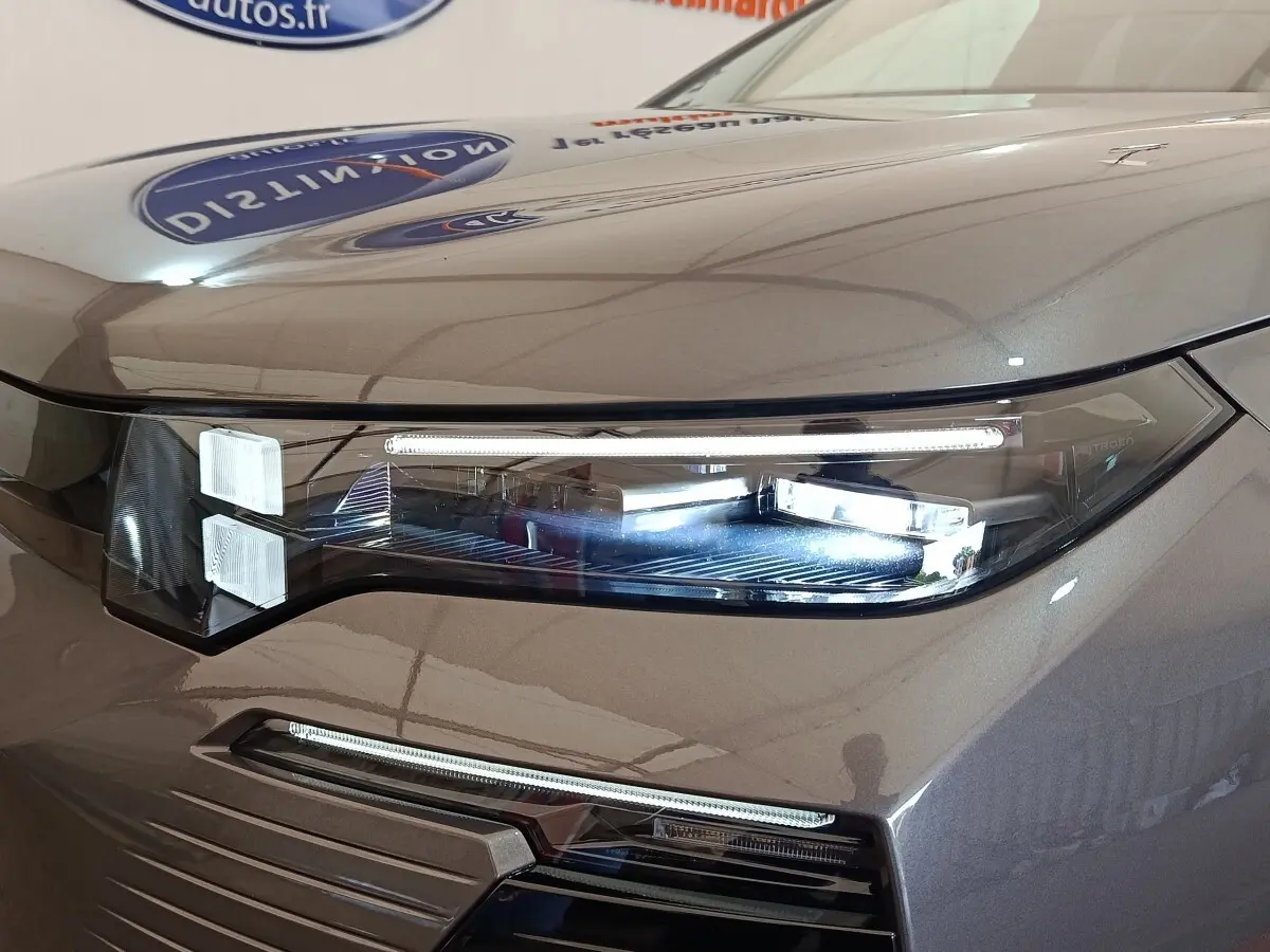 Gros plan sur le phare avant droit LED d'une Citroën C5 hybride gris foncé avec éclairage diurne fin et moderne.