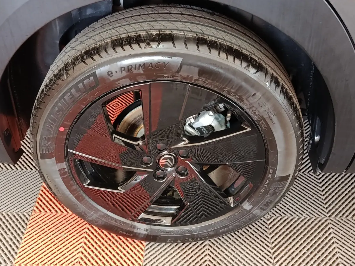 Gros plan sur la roue avant droite gris foncé d'une Citroën C5 Hybride avec jante noire au design géométrique.