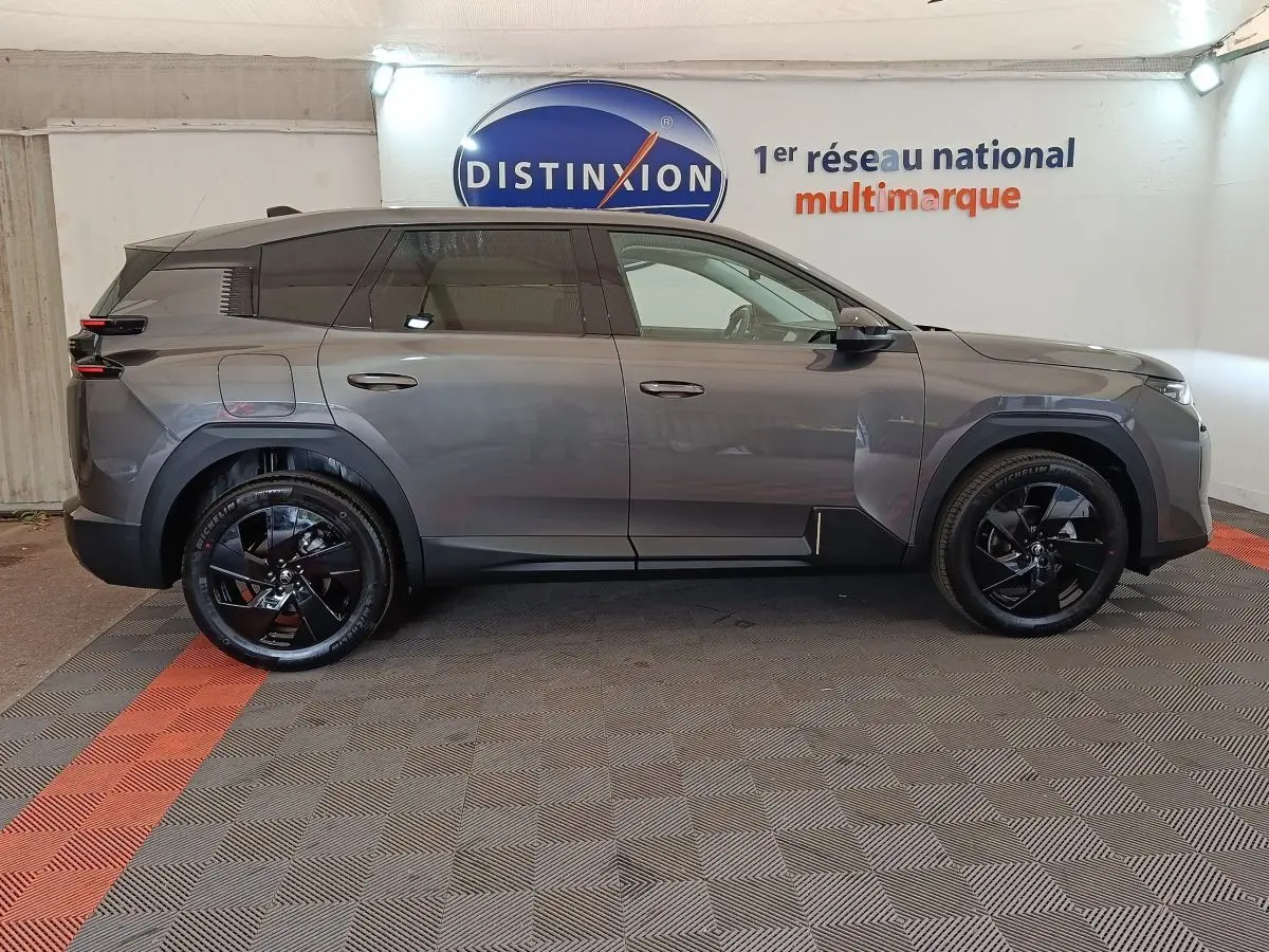 Vue de profil côté gauche d'une Citroën C5 hybride gris foncé avec jantes noires brillantes dans un showroom.