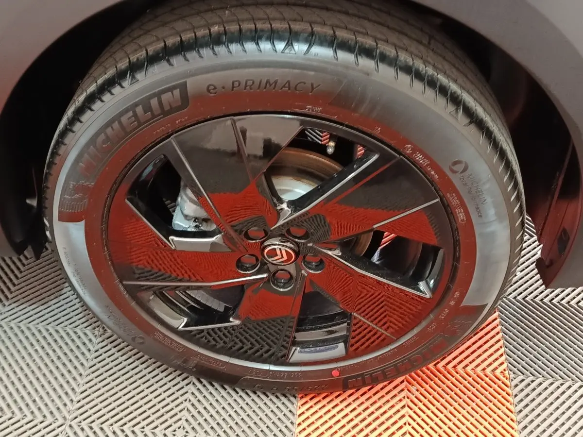 Gros plan sur la roue avant droite de la Citroën C5 hybride gris foncé avec jante noire brillante et logo Citroën central.
