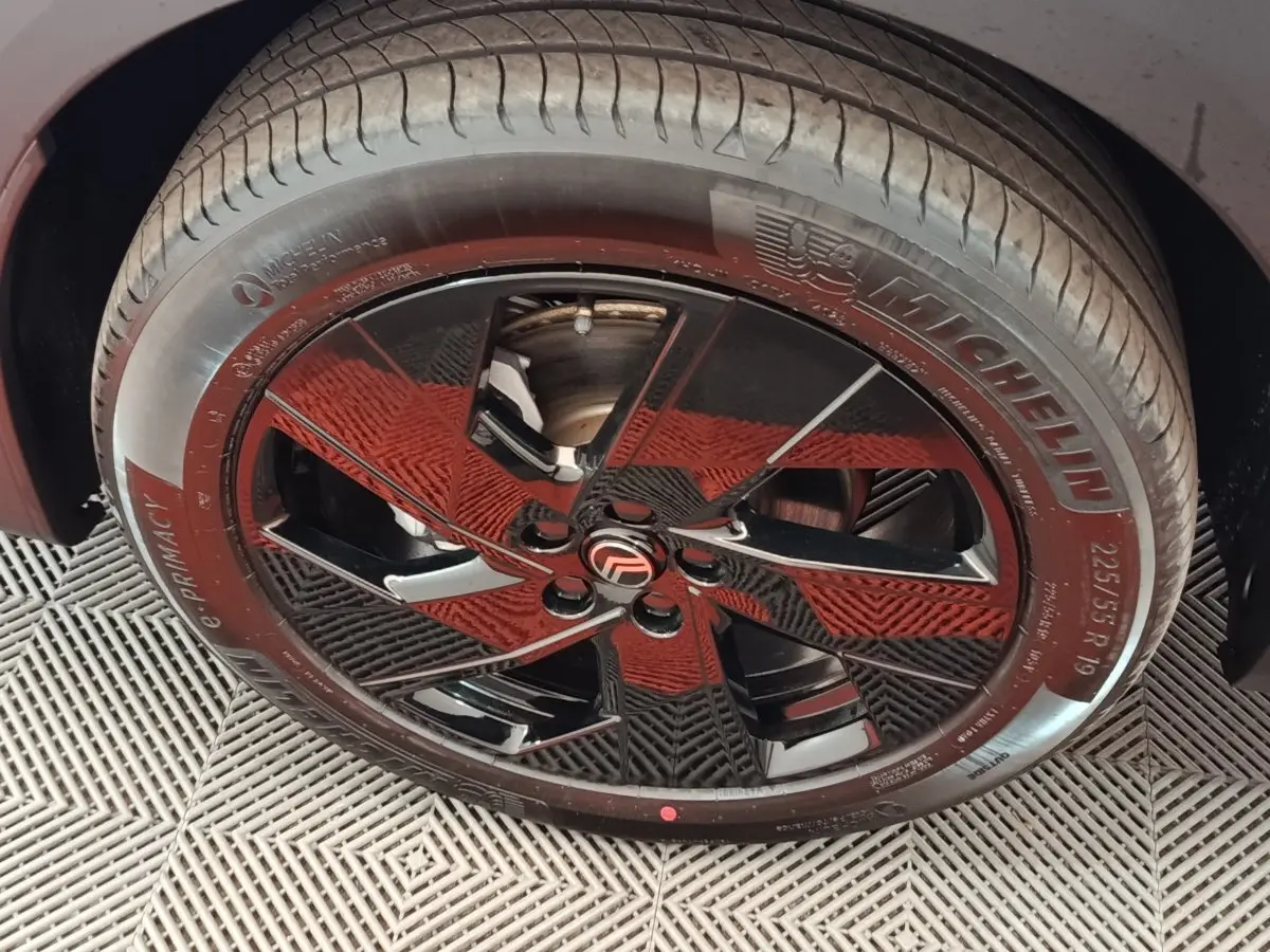 Gros plan sur la roue avant droite avec jante noire brillante et pneu Michelin du Citroën C5 hybride gris foncé.