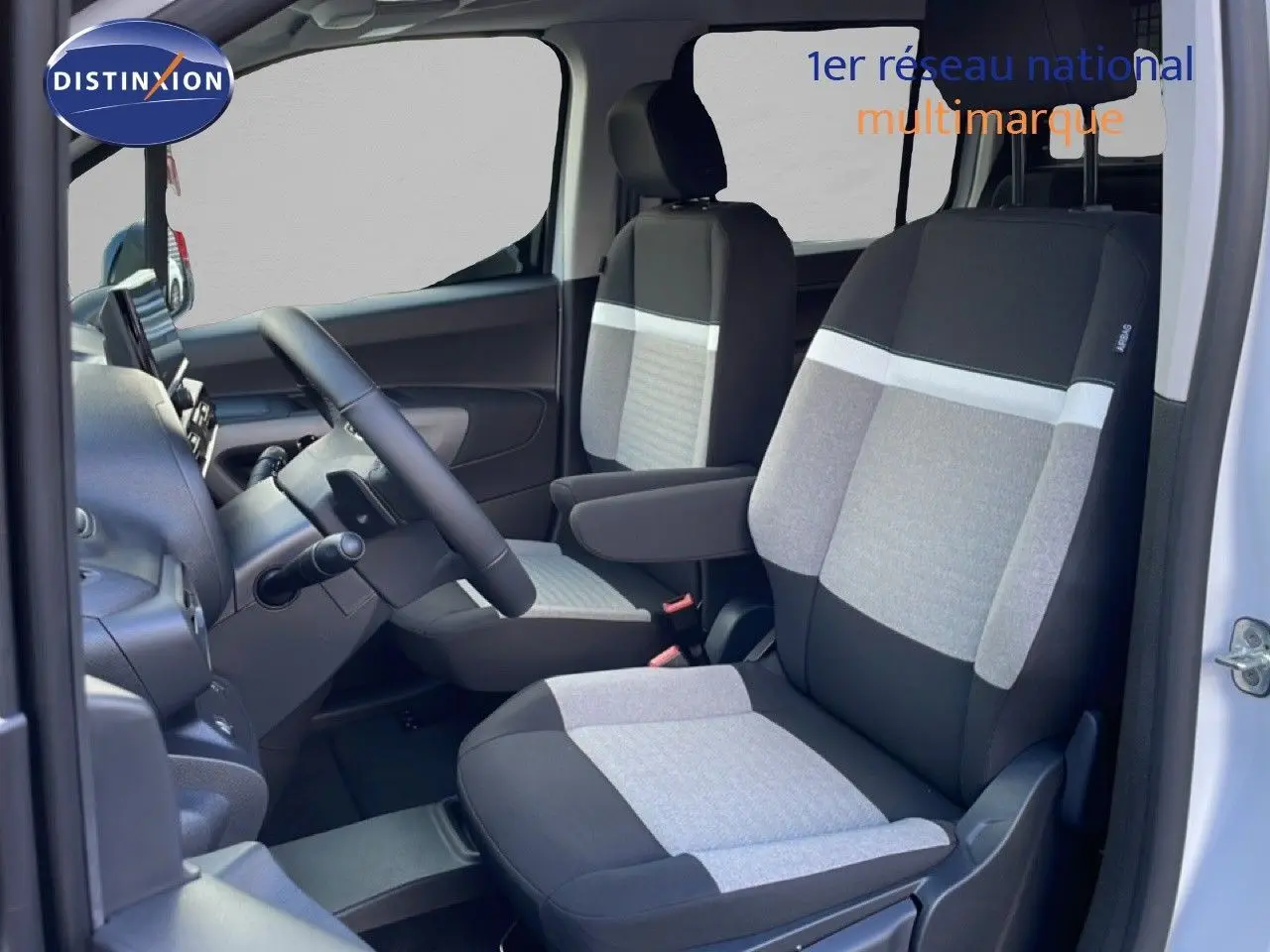Vue intérieure côté gauche du Citroën Berlingo blanc glacier 2025, sièges tissu bicolore avec accoudoir conducteur.