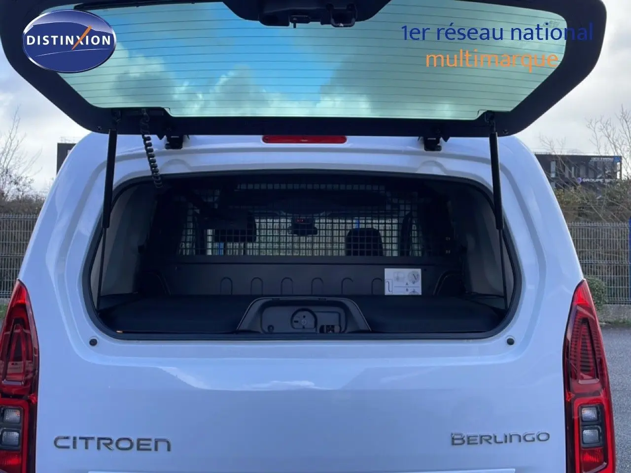Vue arrière ouverte du Citroën Berlingo blanc glacier 2025, mettant en valeur le coffre spacieux et la grille de séparation intérieure.