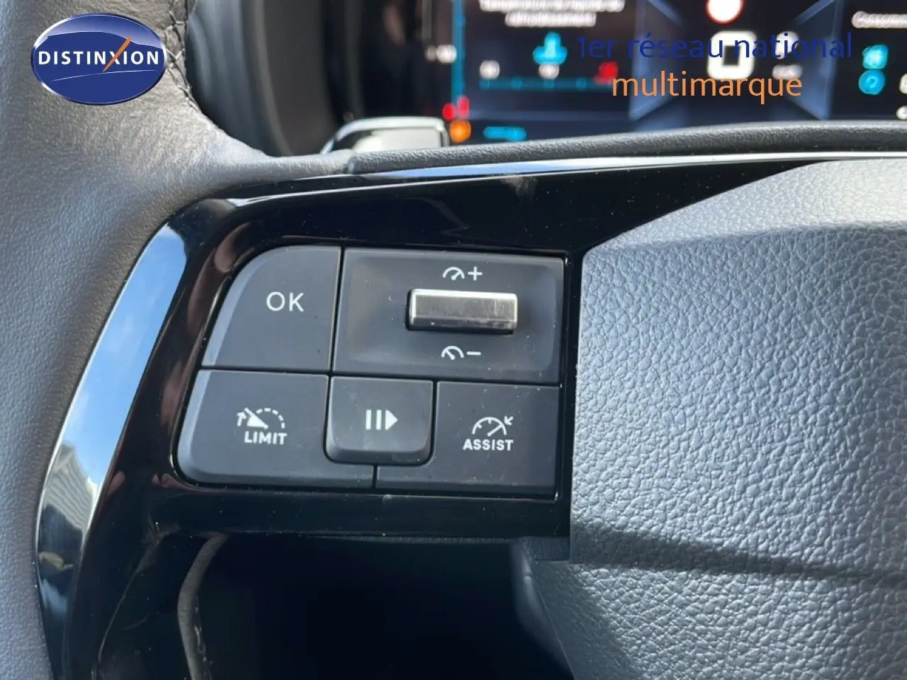 Gros plan sur les commandes au volant noir du Citroën Berlingo blanc glacier, mettant en valeur les boutons d'assistance et de limitation.
