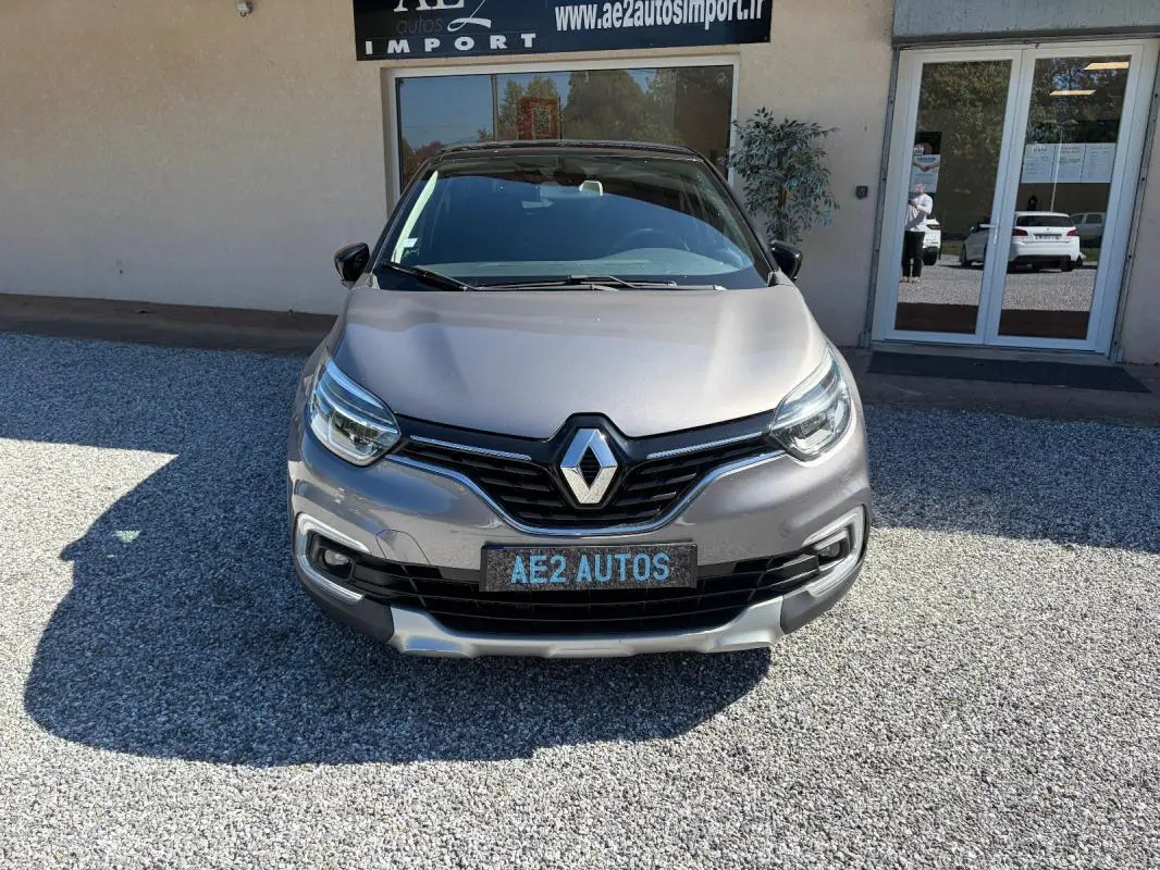 Vue avant d'un Renault Captur gris métallisé 2017 avec calandre noire et plaque AE2 AUTOS visible.
