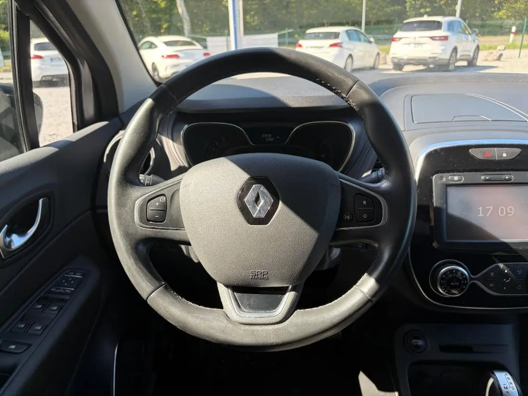 Vue centrée sur le volant multifonctions noir du Renault Captur gris, avec tableau de bord et écran tactile visibles.