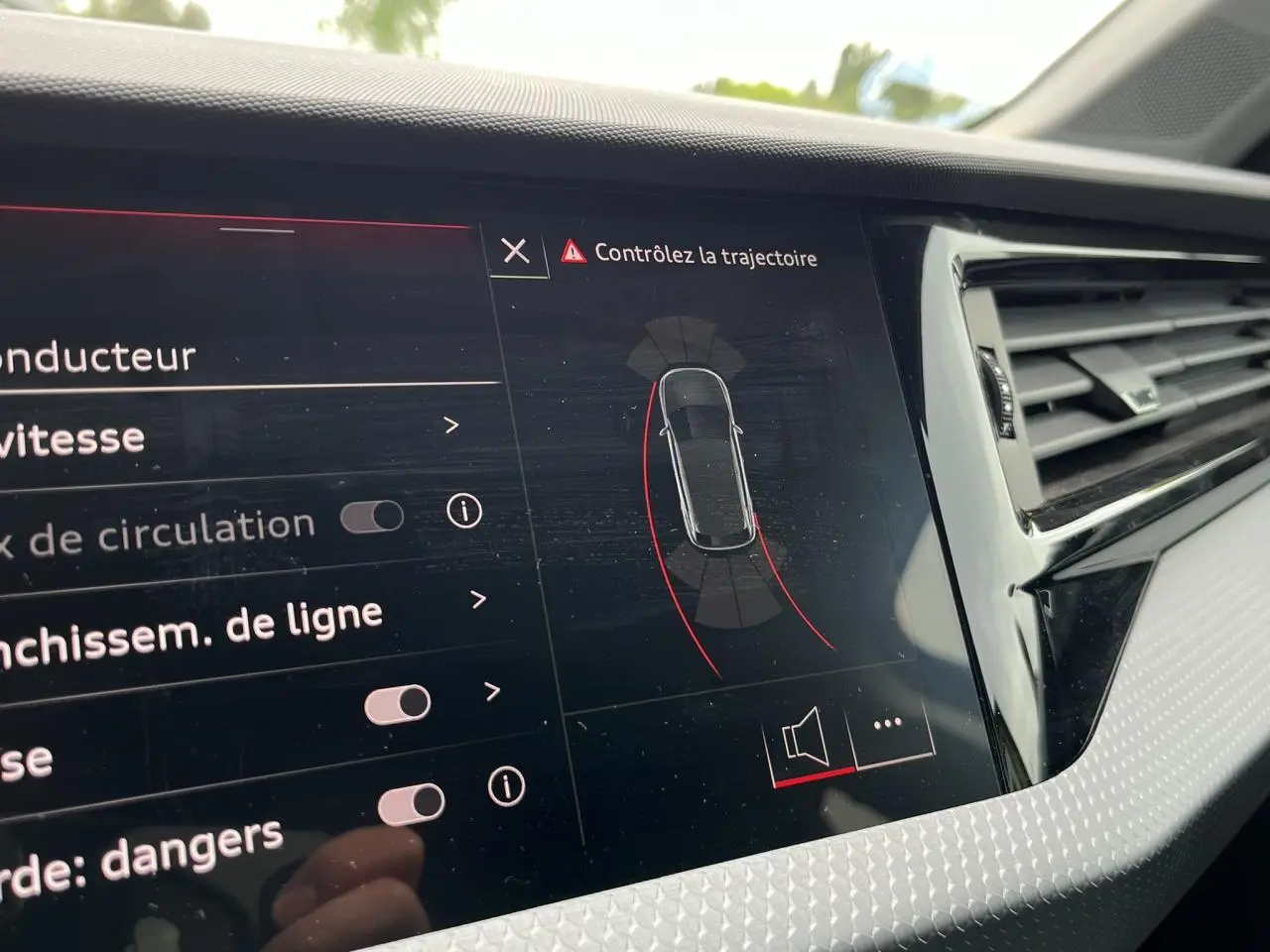 Vue rapprochée de l'écran central de l'Audi A1 Allstreet jaune Python affichant l'aide au stationnement avec trajectoire.