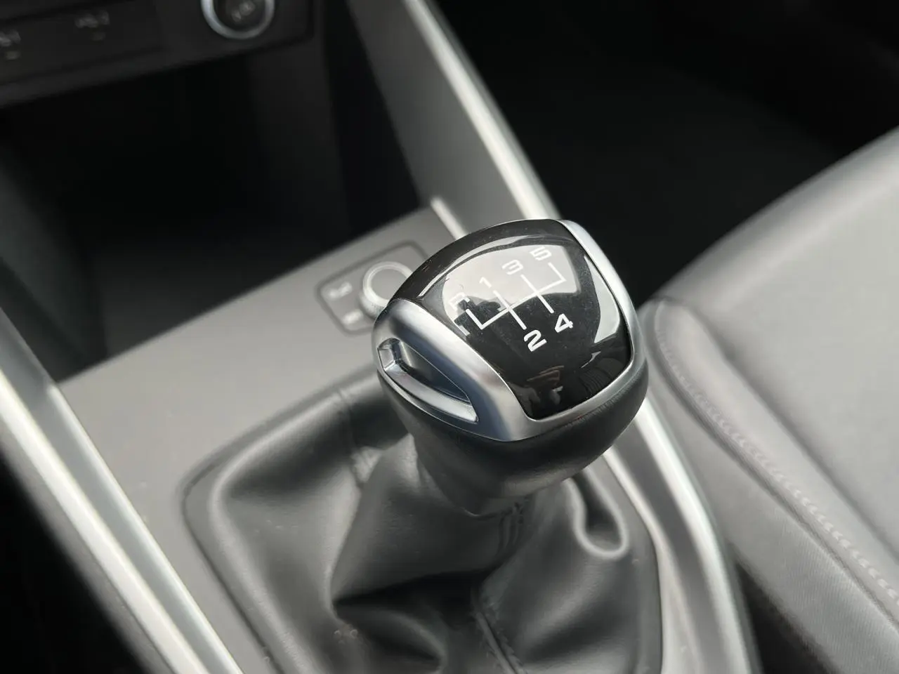 Le levier de vitesses manuel noir de l'Audi A1 Allstreet 25 TFSI, vu en gros plan depuis l'intérieur.