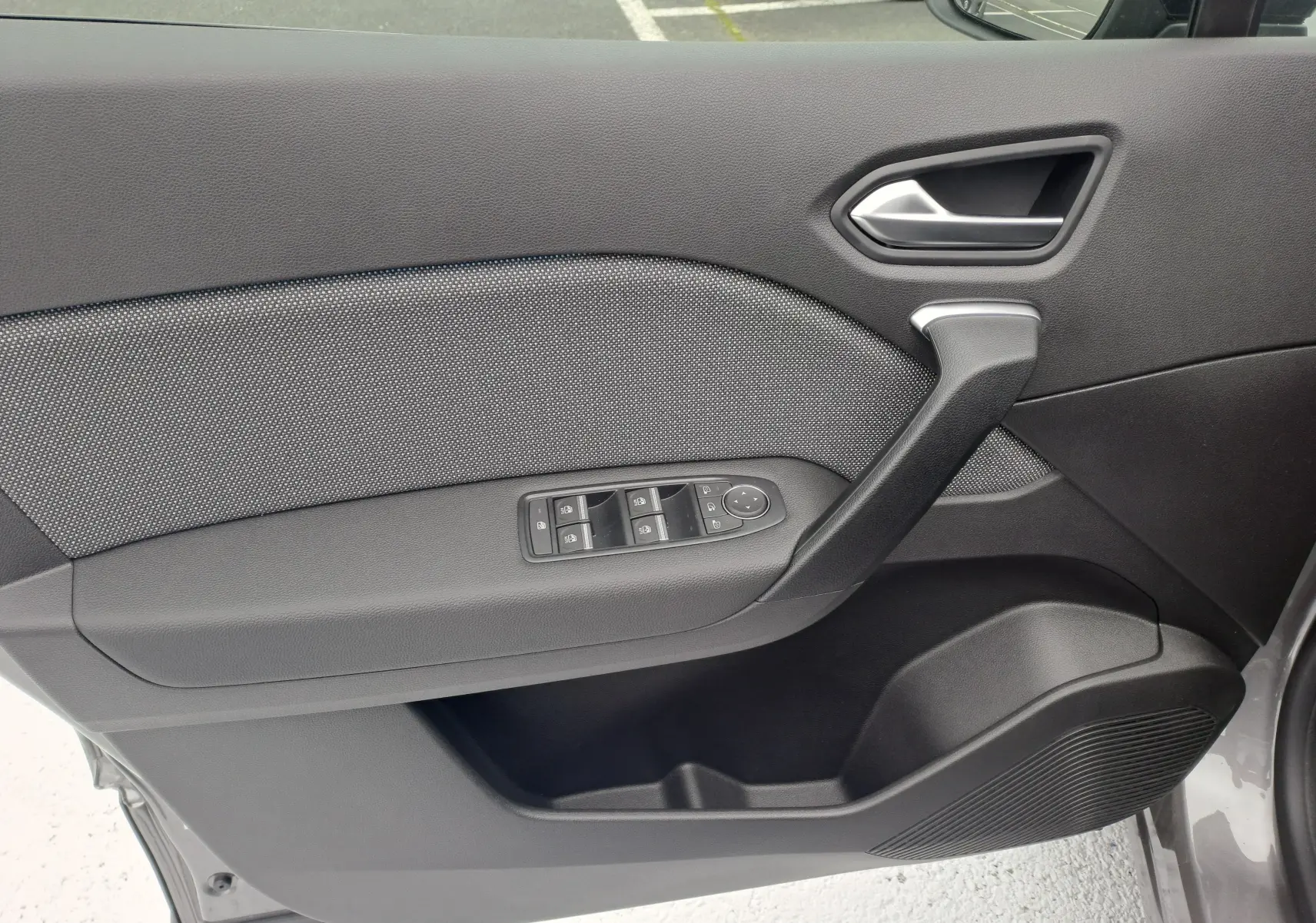 Intérieur côté gauche de la porte avant d'une Renault Symbioz gris Cassiope avec commandes électriques et poignée noire.