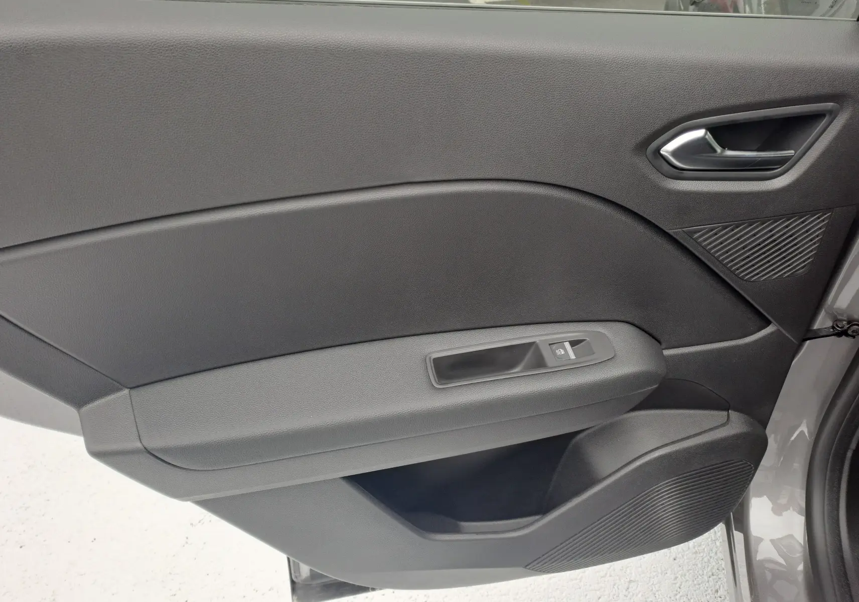 Intérieur côté gauche de la porte avant d'une Renault Symbioz gris Cassiope avec poignée argent et commande de vitre électrique.