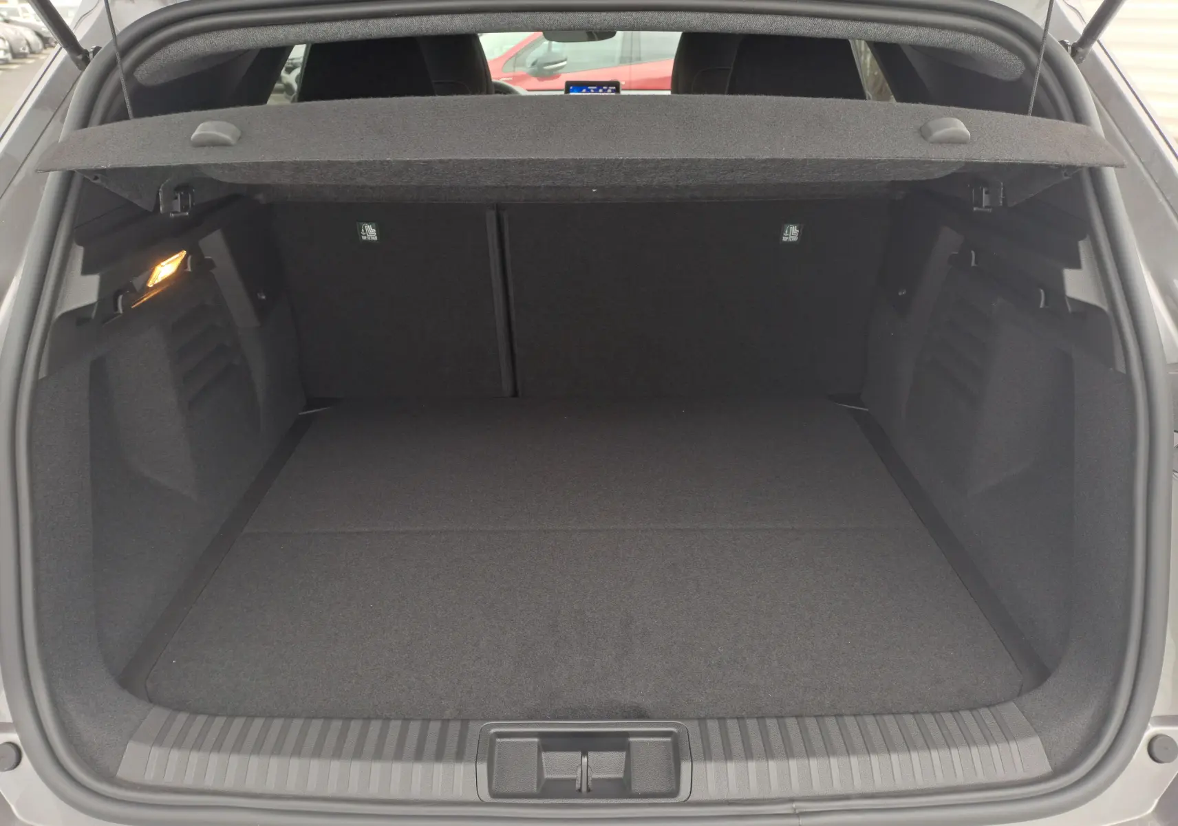 Coffre ouvert du Renault Symbioz gris Cassiope, montrant un espace de chargement propre et bien éclairé.