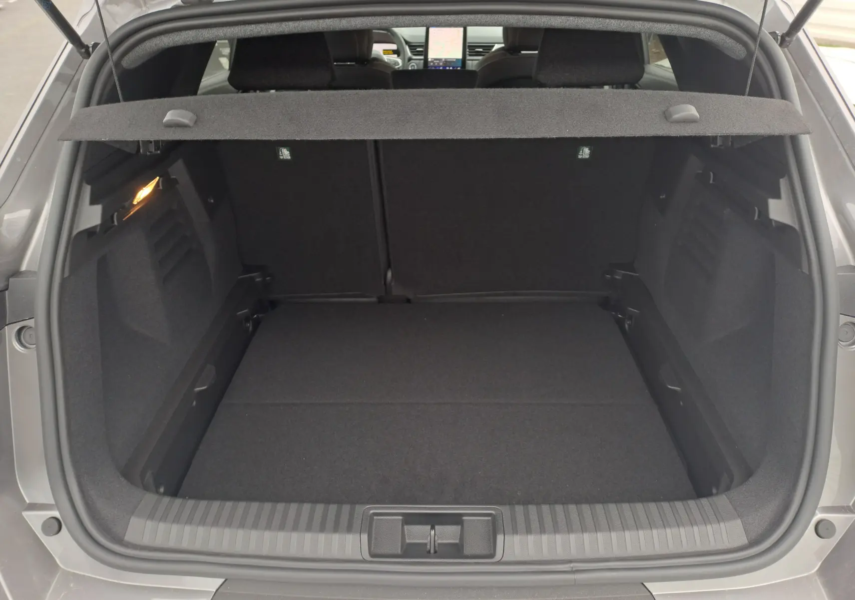 Coffre ouvert vu de l'arrière d'une Renault Symbioz gris Cassiope, avec cache-bagages et intérieur noir.