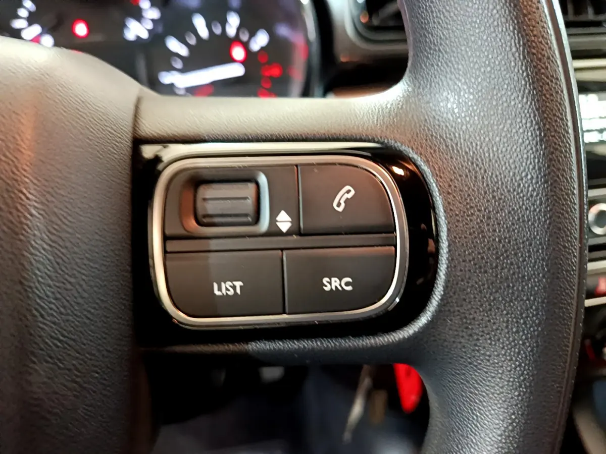 Gros plan sur les commandes multifonctions du volant noir de la Citroën C3 PureTech 68 BVM Feel 2018.