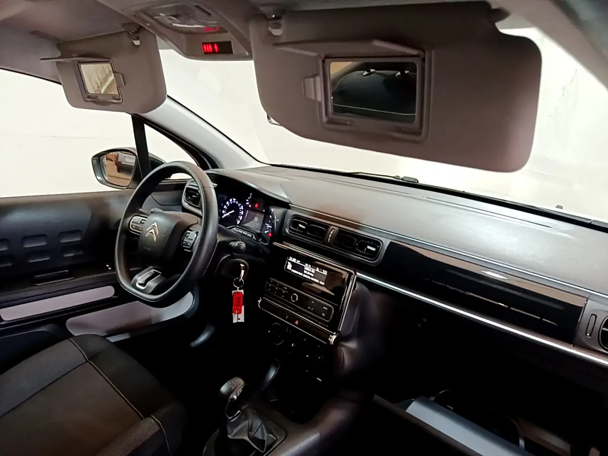 Intérieur avant droit de la Citroën C3 blanche, volant multifonctions, tableau de bord et écran central visibles.