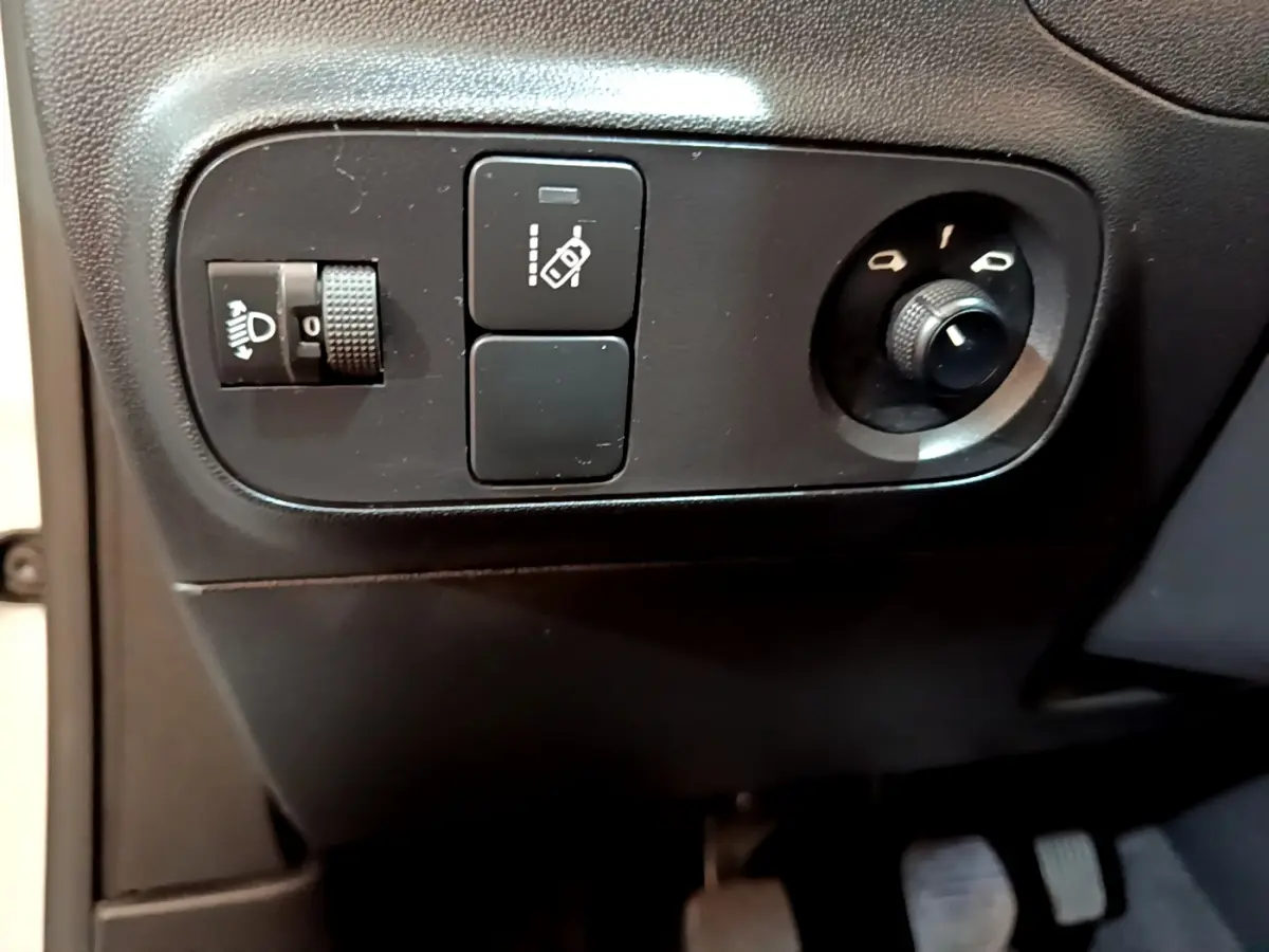Gros plan sur les commandes de réglage des phares et des rétroviseurs côté conducteur d'une Citroën C3 blanche PureTech 2018.
